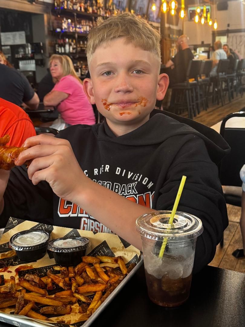 A young guest giving a thumbs up over a plate of fries at The Keg