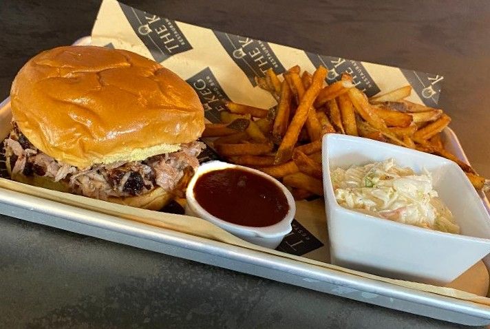 Stacked sandwich with hand-cut fries and coleslaw on a metal tray
